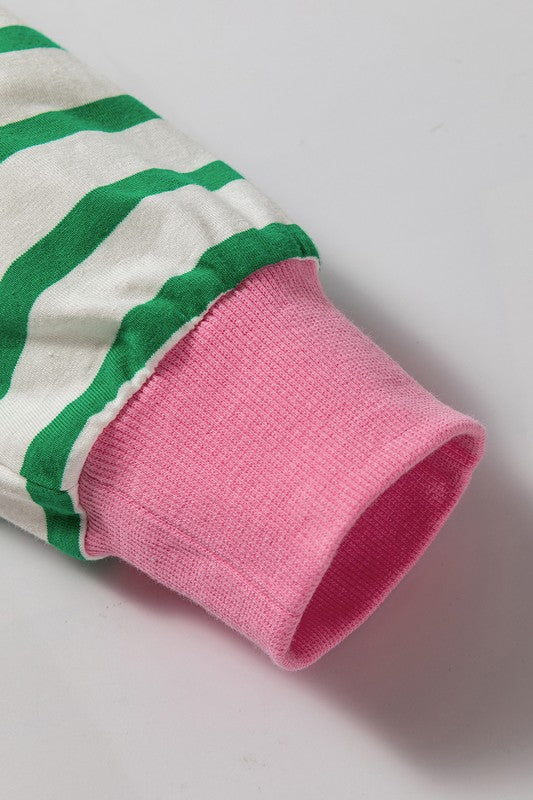 A person wearing the Cotton Stripe Drop Shoulder Sweatshirt, which features green stripes and pink cuffs, is facing away from the camera against a pink background.