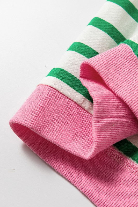 A person wearing the Cotton Stripe Drop Shoulder Sweatshirt, which features green stripes and pink cuffs, is facing away from the camera against a pink background.