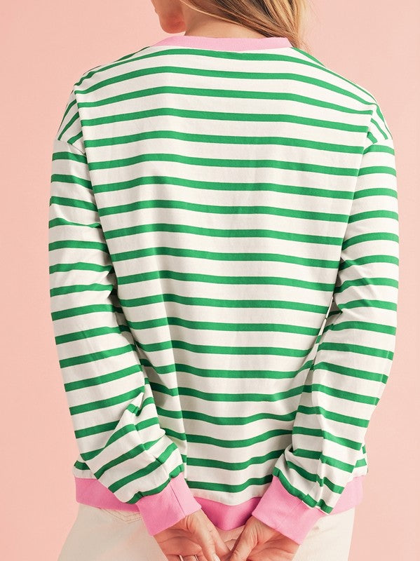 A person wearing the Cotton Stripe Drop Shoulder Sweatshirt, which features green stripes and pink cuffs, is facing away from the camera against a pink background.