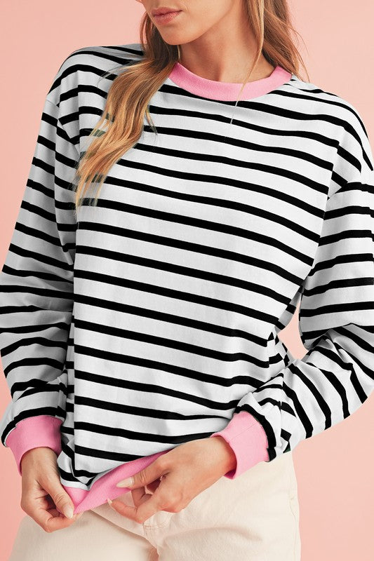 A person wearing the Cotton Stripe Drop Shoulder Sweatshirt, which features green stripes and pink cuffs, is facing away from the camera against a pink background.