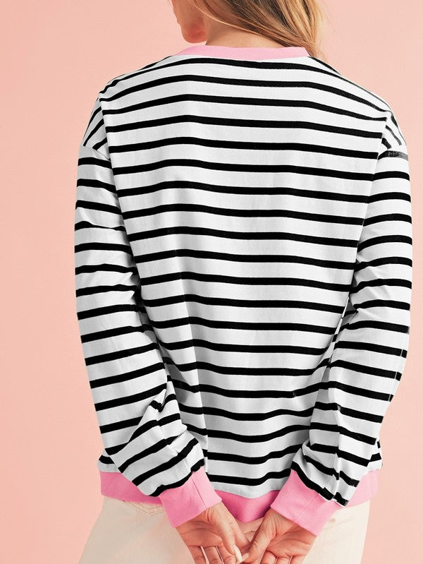 A person wearing the Cotton Stripe Drop Shoulder Sweatshirt, which features green stripes and pink cuffs, is facing away from the camera against a pink background.