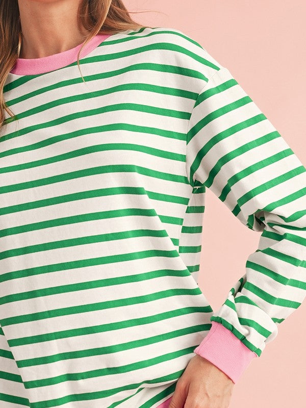 A person wearing the Cotton Stripe Drop Shoulder Sweatshirt, which features green stripes and pink cuffs, is facing away from the camera against a pink background.