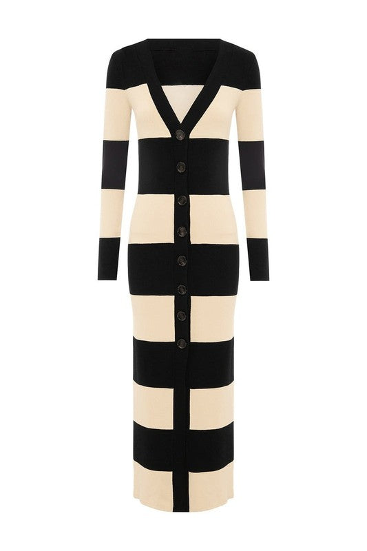 A person stands wearing the WOMEN FASHION CARDIGAN SWEATER DRESS, a long, black-and-white striped cardigan dress complete with buttons down the front and long sleeves.