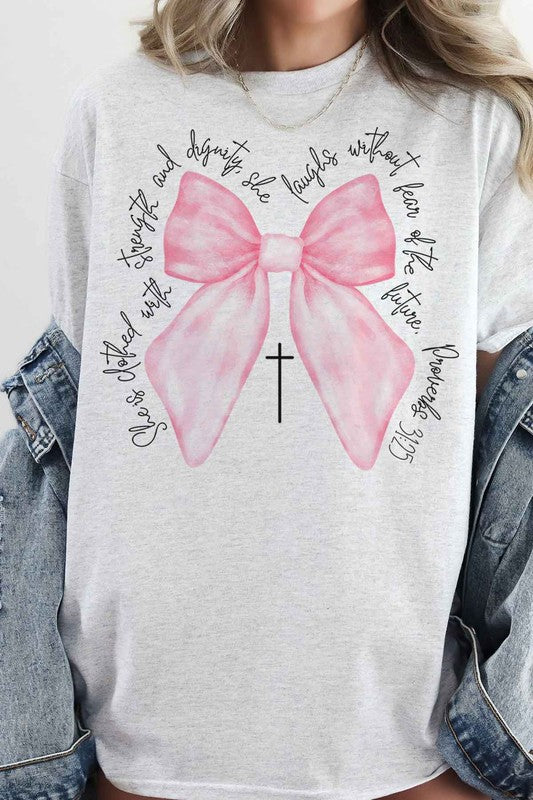 Person taking a mirror selfie wearing the PROVERBS PINK BOW CHRISTIAN OVERSIZED GRAPHIC TEE, made of premium cotton, featuring a large pink bow, a small cross below it, and cursive text around the design.