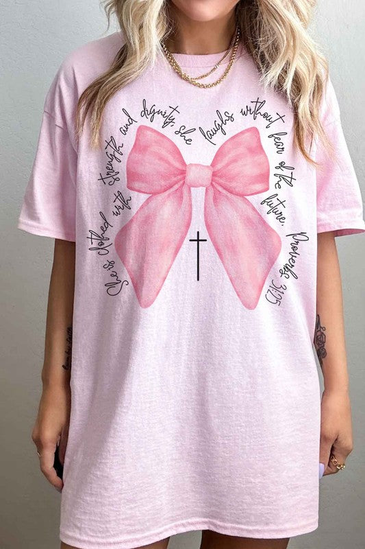 Person taking a mirror selfie wearing the PROVERBS PINK BOW CHRISTIAN OVERSIZED GRAPHIC TEE, made of premium cotton, featuring a large pink bow, a small cross below it, and cursive text around the design.