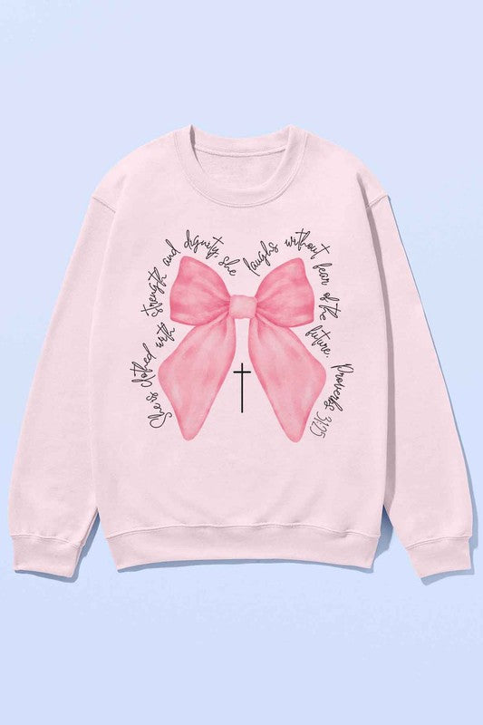 A person is wearing the PROVERBS PINK BOW CHRISTIAN OVERSIZED SWEATSHIRT made of premium cotton. The light gray design features a large pink bow with a black cross in the center and cursive text around it. Paired with cowboy boots, this Christian-inspired look blends comfort and style effortlessly.