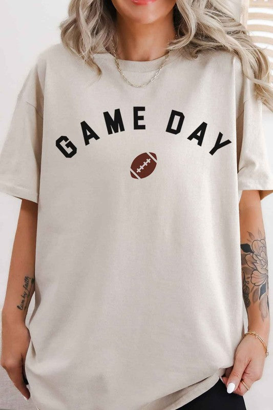 A person wearing the GAME DAY FOOTBALL TAILGATE GRAPHIC TEE, made from premium cotton in beige, with "GAME DAY" and a football image printed on the front, ready for a football tailgate.