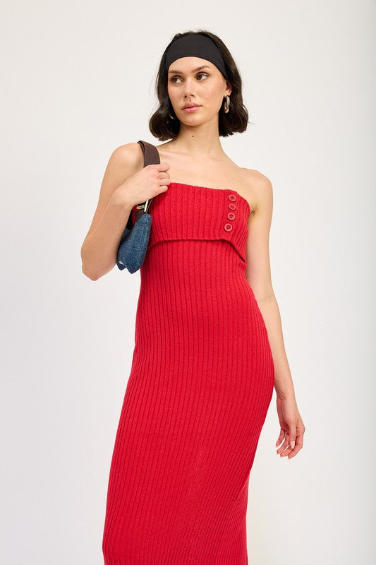 A woman stands against a plain background, wearing a red Fold Over Ribbed Tube Dress with buttons on the bodice. Made from imported fabric, she pairs it with a black headband, a small shoulder bag, and black flip-flops. This outfit is size small.