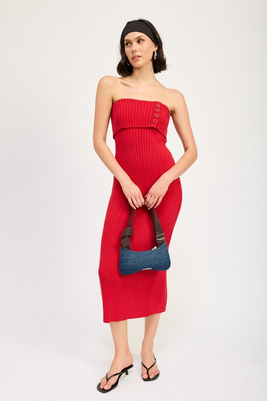 A woman stands against a plain background, wearing a red Fold Over Ribbed Tube Dress with buttons on the bodice. Made from imported fabric, she pairs it with a black headband, a small shoulder bag, and black flip-flops. This outfit is size small.