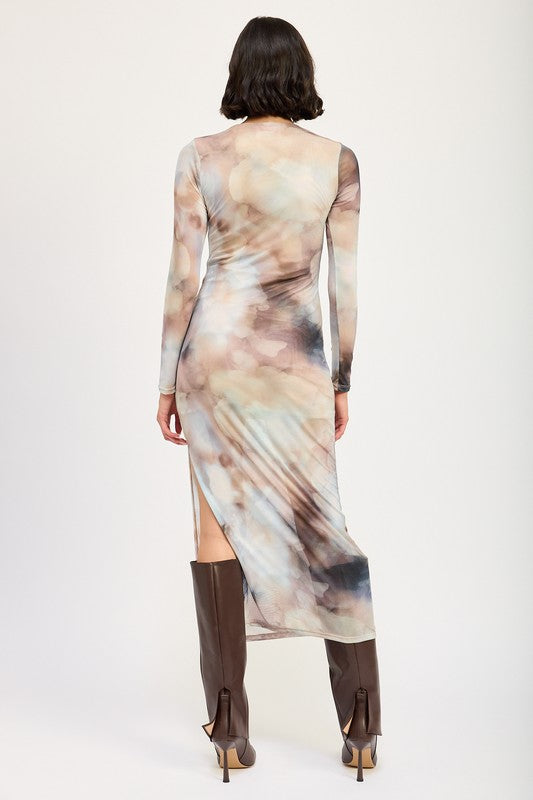 A person models a LONG SLEEVE MAXI DRESS WITH SLIT in size small, featuring sheer fabric and a watercolor print, paired with knee-high brown boots against a plain background. The model, standing at 5'9", showcases the dress which is made in the USA.