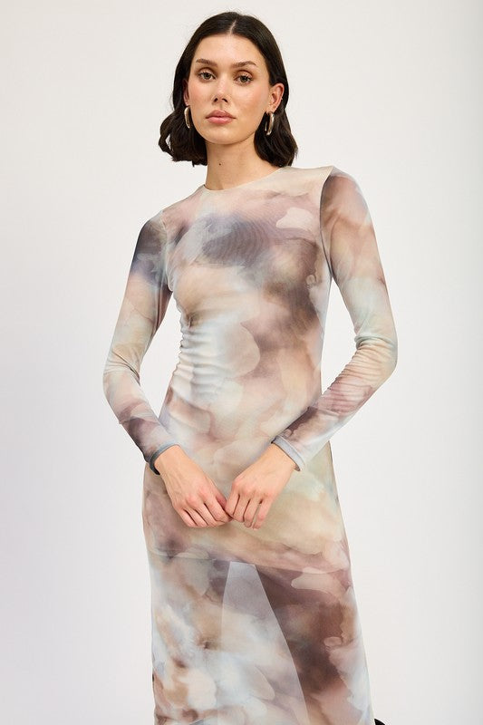 A person models a LONG SLEEVE MAXI DRESS WITH SLIT in size small, featuring sheer fabric and a watercolor print, paired with knee-high brown boots against a plain background. The model, standing at 5'9", showcases the dress which is made in the USA.