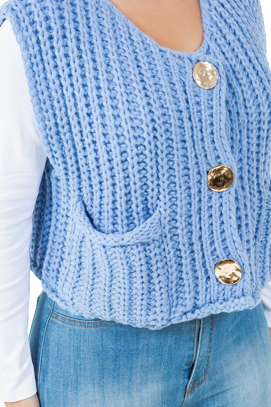 A woman posing with one hand in her pocket is wearing a WOMEN FASHION KNITWEAR VEST with large buttons over a white long sleeve shirt and blue jeans.