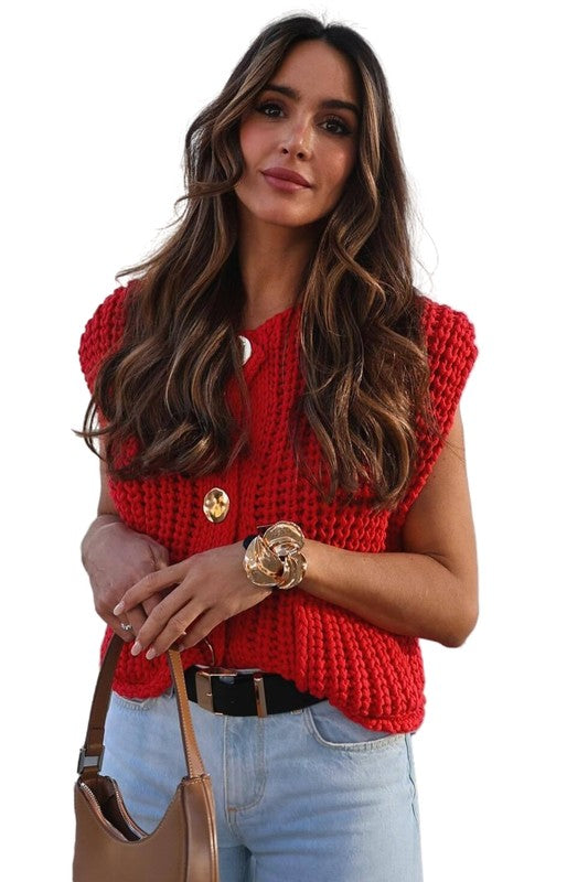 A woman with long, wavy hair wears a sleeveless WOMEN FASHION KNITWEAR VEST in red adorned with large buttons, paired with light blue jeans and a brown belt. She is holding a tan handbag and has a bracelet on her left wrist, completing her chic look.