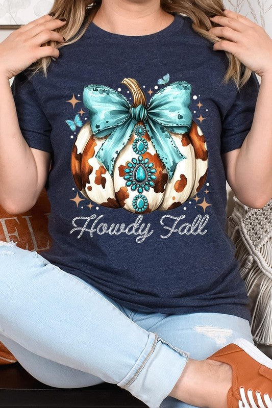 Person wearing the Howdy Fall Western Pumpkin Graphic Tee, featuring an illustrated pumpkin adorned with a blue bow and turquoise jewelry, along with the text "Howdy Fall." This beige unisex crew neck shirt pairs perfectly with their denim jacket.