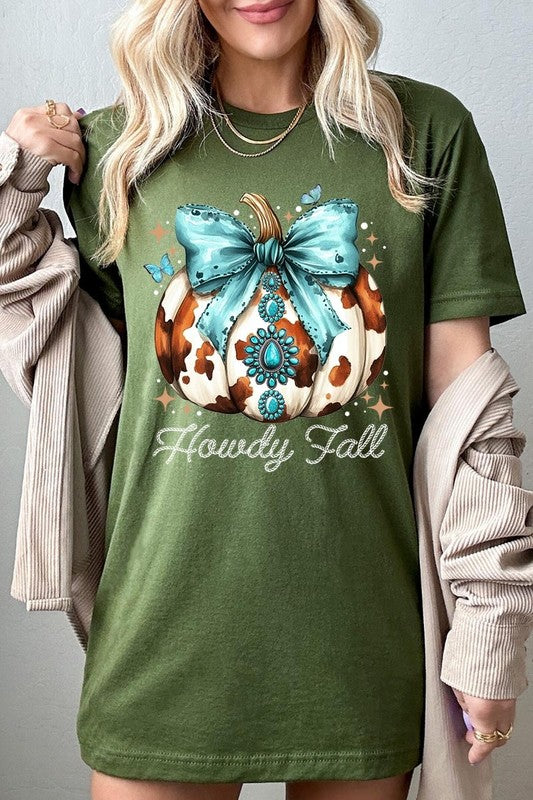 Person wearing the Howdy Fall Western Pumpkin Graphic Tee, featuring an illustrated pumpkin adorned with a blue bow and turquoise jewelry, along with the text "Howdy Fall." This beige unisex crew neck shirt pairs perfectly with their denim jacket.