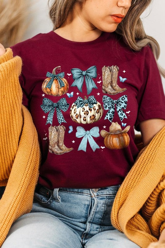 Person wearing a Turquoise Bow Western Fall Graphic Tee featuring illustrations of pumpkins, bows, cowboy hats, and boots adorned with blue and leopard print patterns. The high-quality printed design pairs perfectly with denim shorts and a denim jacket.