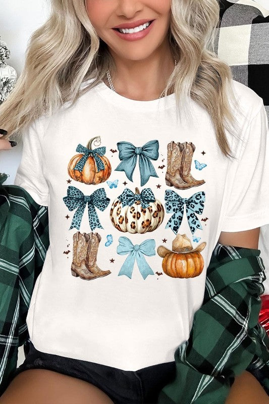 Person wearing a Turquoise Bow Western Fall Graphic Tee featuring illustrations of pumpkins, bows, cowboy hats, and boots adorned with blue and leopard print patterns. The high-quality printed design pairs perfectly with denim shorts and a denim jacket.