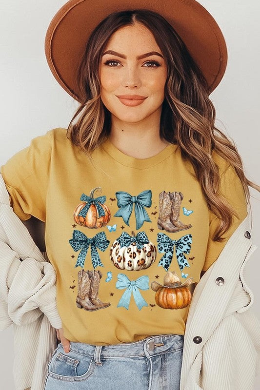 Person wearing a Turquoise Bow Western Fall Graphic Tee featuring illustrations of pumpkins, bows, cowboy hats, and boots adorned with blue and leopard print patterns. The high-quality printed design pairs perfectly with denim shorts and a denim jacket.