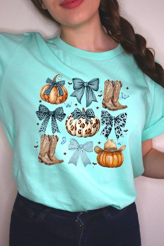 Person wearing a Turquoise Bow Western Fall Graphic Tee featuring illustrations of pumpkins, bows, cowboy hats, and boots adorned with blue and leopard print patterns. The high-quality printed design pairs perfectly with denim shorts and a denim jacket.