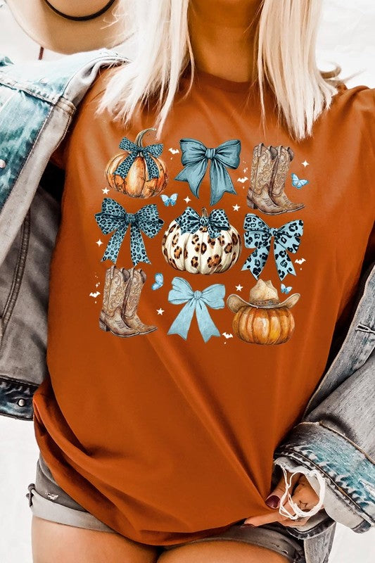 Person wearing a Turquoise Bow Western Fall Graphic Tee featuring illustrations of pumpkins, bows, cowboy hats, and boots adorned with blue and leopard print patterns. The high-quality printed design pairs perfectly with denim shorts and a denim jacket.