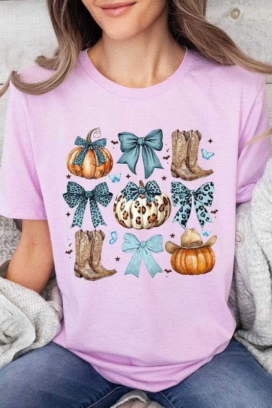 Person wearing a Turquoise Bow Western Fall Graphic Tee featuring illustrations of pumpkins, bows, cowboy hats, and boots adorned with blue and leopard print patterns. The high-quality printed design pairs perfectly with denim shorts and a denim jacket.