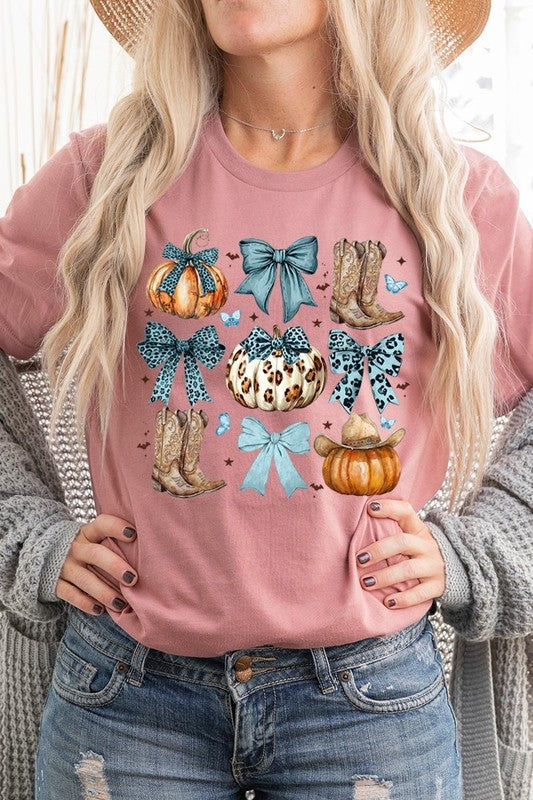 Person wearing a Turquoise Bow Western Fall Graphic Tee featuring illustrations of pumpkins, bows, cowboy hats, and boots adorned with blue and leopard print patterns. The high-quality printed design pairs perfectly with denim shorts and a denim jacket.