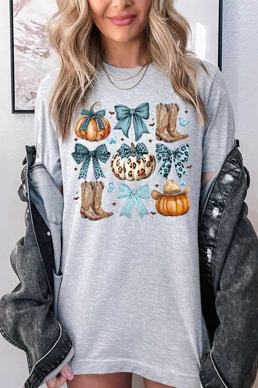 Person wearing a Turquoise Bow Western Fall Graphic Tee featuring illustrations of pumpkins, bows, cowboy hats, and boots adorned with blue and leopard print patterns. The high-quality printed design pairs perfectly with denim shorts and a denim jacket.