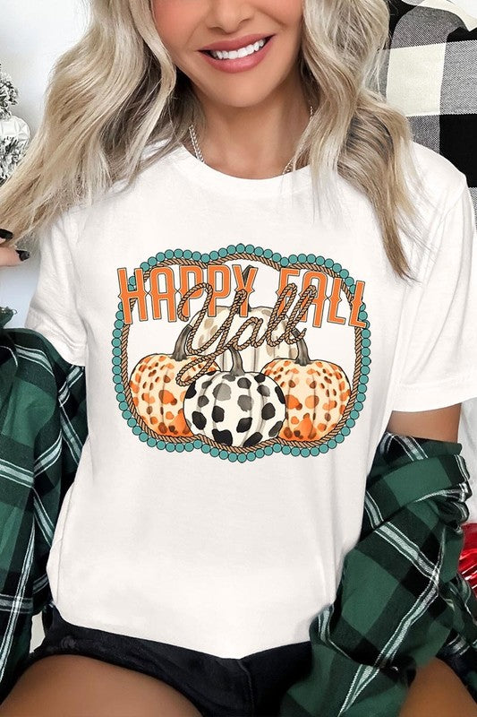 A person wearing a top-quality "Happy Fall Y'all" Graphic Tee featuring a design with three patterned pumpkins, paired with jeans and an orange cardigan, holds a pumpkin-shaped mug.