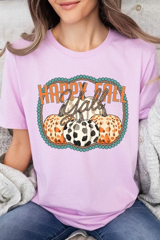 A person wearing a top-quality "Happy Fall Y'all" Graphic Tee featuring a design with three patterned pumpkins, paired with jeans and an orange cardigan, holds a pumpkin-shaped mug.