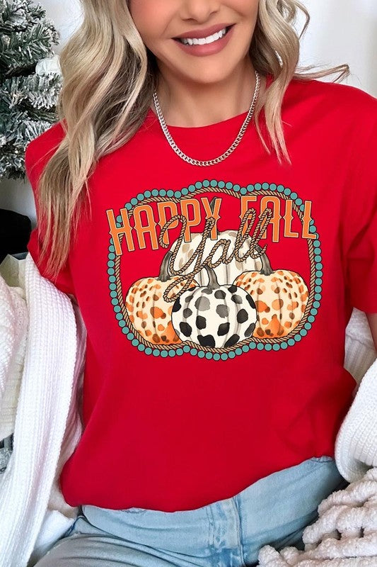 A person wearing a top-quality "Happy Fall Y'all" Graphic Tee featuring a design with three patterned pumpkins, paired with jeans and an orange cardigan, holds a pumpkin-shaped mug.