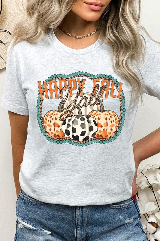 A person wearing a top-quality "Happy Fall Y'all" Graphic Tee featuring a design with three patterned pumpkins, paired with jeans and an orange cardigan, holds a pumpkin-shaped mug.