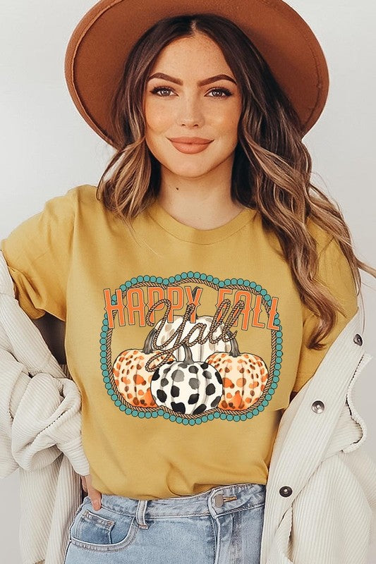 A person wearing a top-quality "Happy Fall Y'all" Graphic Tee featuring a design with three patterned pumpkins, paired with jeans and an orange cardigan, holds a pumpkin-shaped mug.