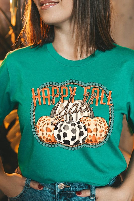 A person wearing a top-quality "Happy Fall Y'all" Graphic Tee featuring a design with three patterned pumpkins, paired with jeans and an orange cardigan, holds a pumpkin-shaped mug.