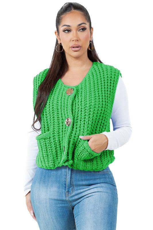 A woman with long dark hair wearing a green WOMEN FASHION KNITWEAR VEST with large buttons over a white long-sleeve shirt and blue jeans.