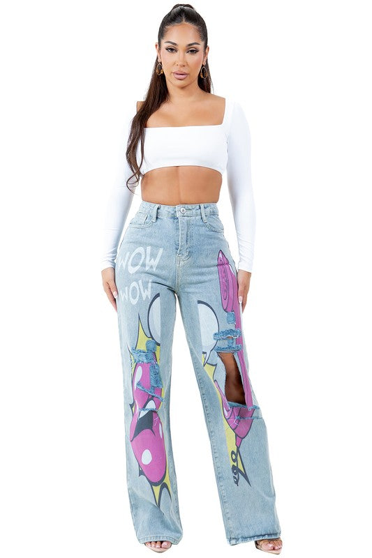 A woman stands wearing a long-sleeve white crop top and WOMEN FASHION DENIM PANTS featuring light blue, high-waist design with comic-style graphics and large knee cutouts.