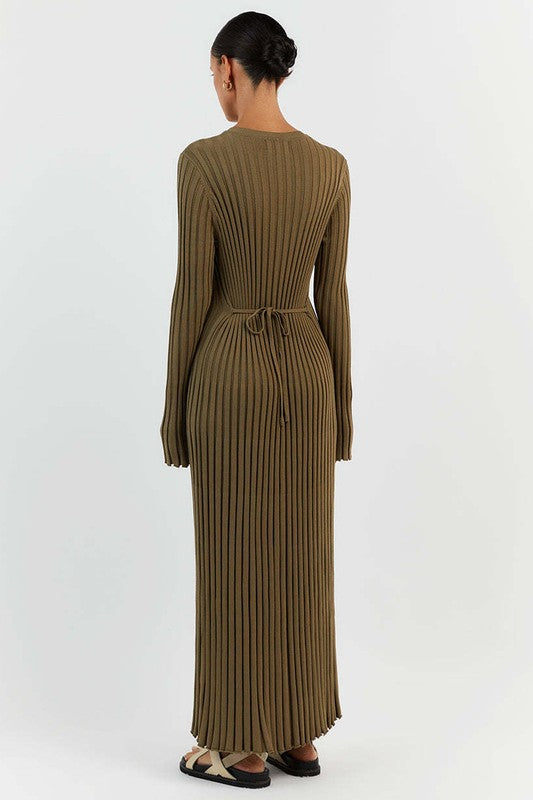 Person standing against a plain background wearing the WOMEN FASHION KNITWEAR LONG MAXI DRESS in olive green, with long sleeves, ribbed texture, a round neckline, and beige sandals.