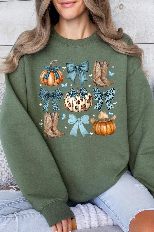 A woman is wearing a high-quality Turquoise Bow Western Fall Fleece Sweatshirt in olive green, featuring pumpkins, cowboy boots, a hat, and turquoise bows. She is seated on a gray, textured surface and wears light blue ripped jeans.