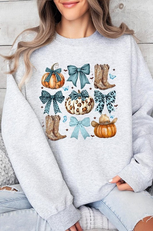 A woman is wearing a high-quality Turquoise Bow Western Fall Fleece Sweatshirt in olive green, featuring pumpkins, cowboy boots, a hat, and turquoise bows. She is seated on a gray, textured surface and wears light blue ripped jeans.