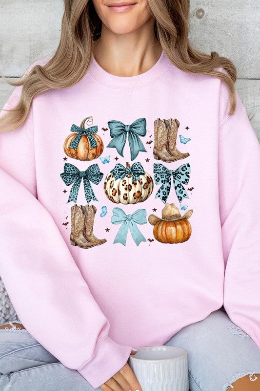 A woman is wearing a high-quality Turquoise Bow Western Fall Fleece Sweatshirt in olive green, featuring pumpkins, cowboy boots, a hat, and turquoise bows. She is seated on a gray, textured surface and wears light blue ripped jeans.