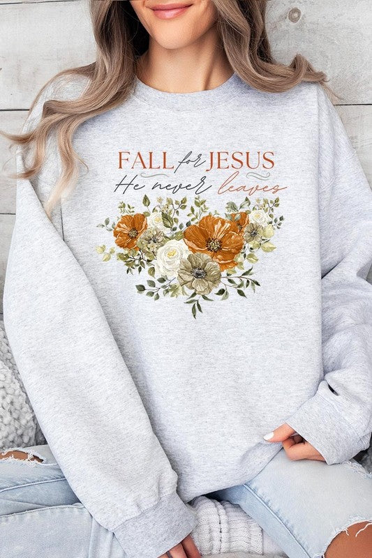 A person wearing a beige "Fall For Jesus He Never Leaves Fleece Sweatshirt" featuring a floral design and the text "FALL for JESUS He never leaves." This unisex crew neck fleece makes an excellent family group gift.