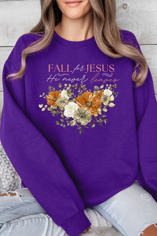 A person wearing a beige "Fall For Jesus He Never Leaves Fleece Sweatshirt" featuring a floral design and the text "FALL for JESUS He never leaves." This unisex crew neck fleece makes an excellent family group gift.