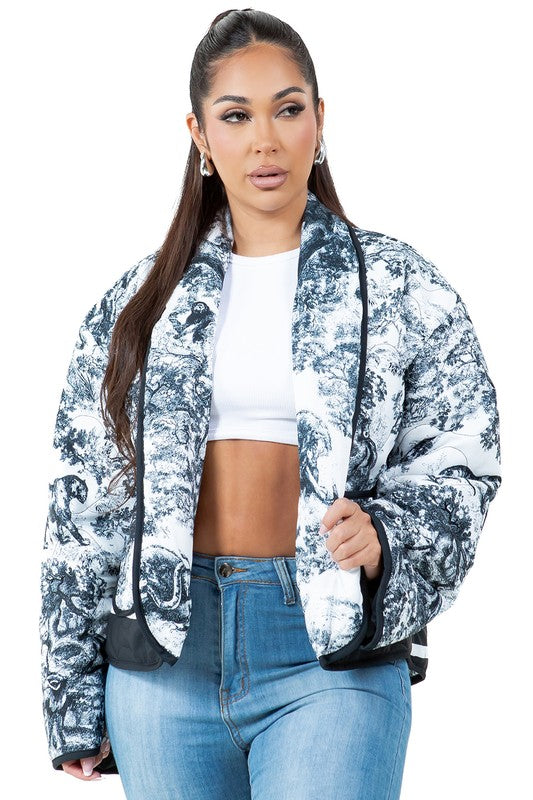 A woman stands facing forward wearing the WOMEN FASHION PUFFER JACKET, which features a blue and white pattern and a stand collar, giving an oversized look. She is also dressed in a white cropped top, blue jeans, and black ankle boots.