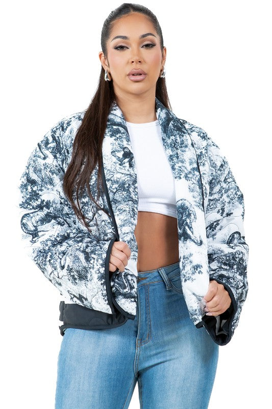 A woman stands facing forward wearing the WOMEN FASHION PUFFER JACKET, which features a blue and white pattern and a stand collar, giving an oversized look. She is also dressed in a white cropped top, blue jeans, and black ankle boots.