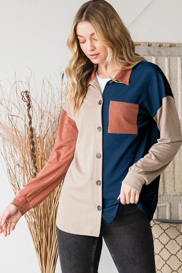 A woman stands indoors wearing the Heimish Full Size Color Block Button Down Shirt, set against a backdrop of a woven tapestry, highlighting her versatile wardrobe.