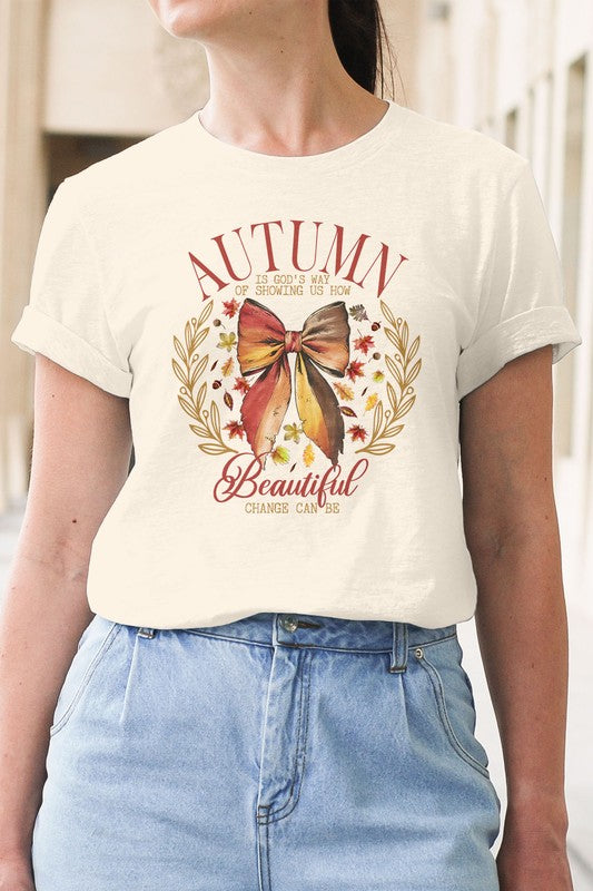 A person wearing the Autumn Fall Vintage Graphic Tee, an eco-friendly white T-shirt featuring a high-quality print of a bow and leaves with the phrase "Autumn shows us how beautiful change can be.