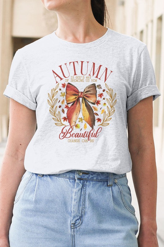 A person wearing the Autumn Fall Vintage Graphic Tee, an eco-friendly white T-shirt featuring a high-quality print of a bow and leaves with the phrase "Autumn shows us how beautiful change can be.