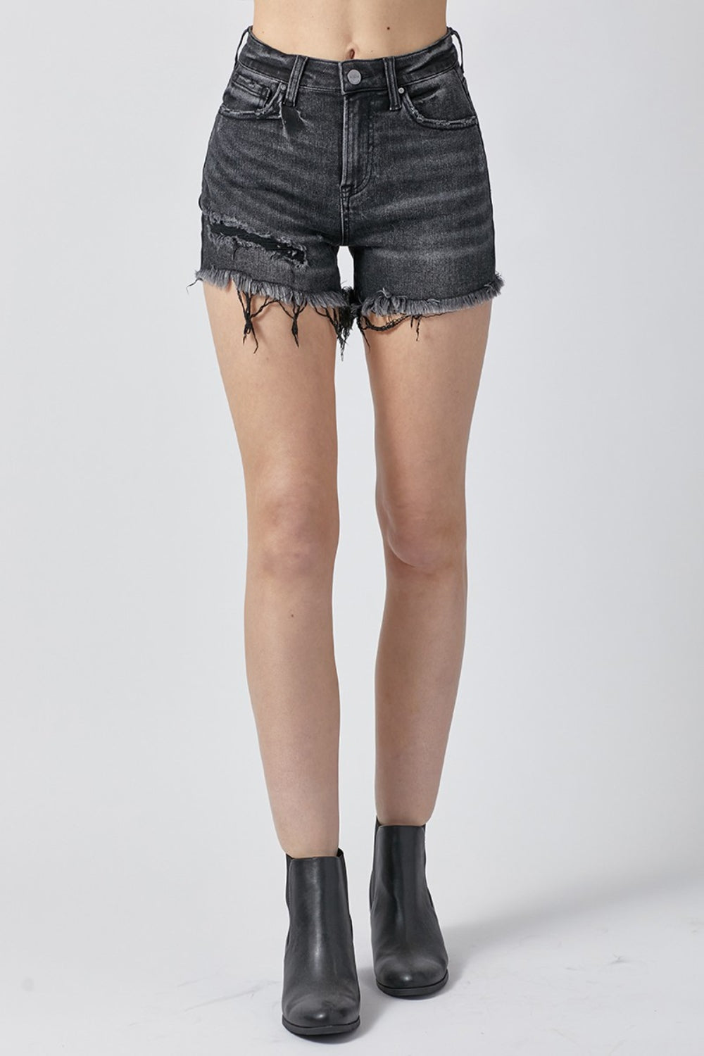 A person wearing RISEN Raw Hem Denim Shorts with Pockets, featuring high-waisted, distressed black design and a button and zipper closure, perfect for summer outfits.