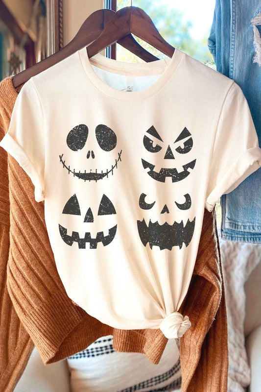 A person wears the SCARY PUMPKINS Graphic Tee, featuring four black, scary pumpkin faces, paired with checkered shorts.