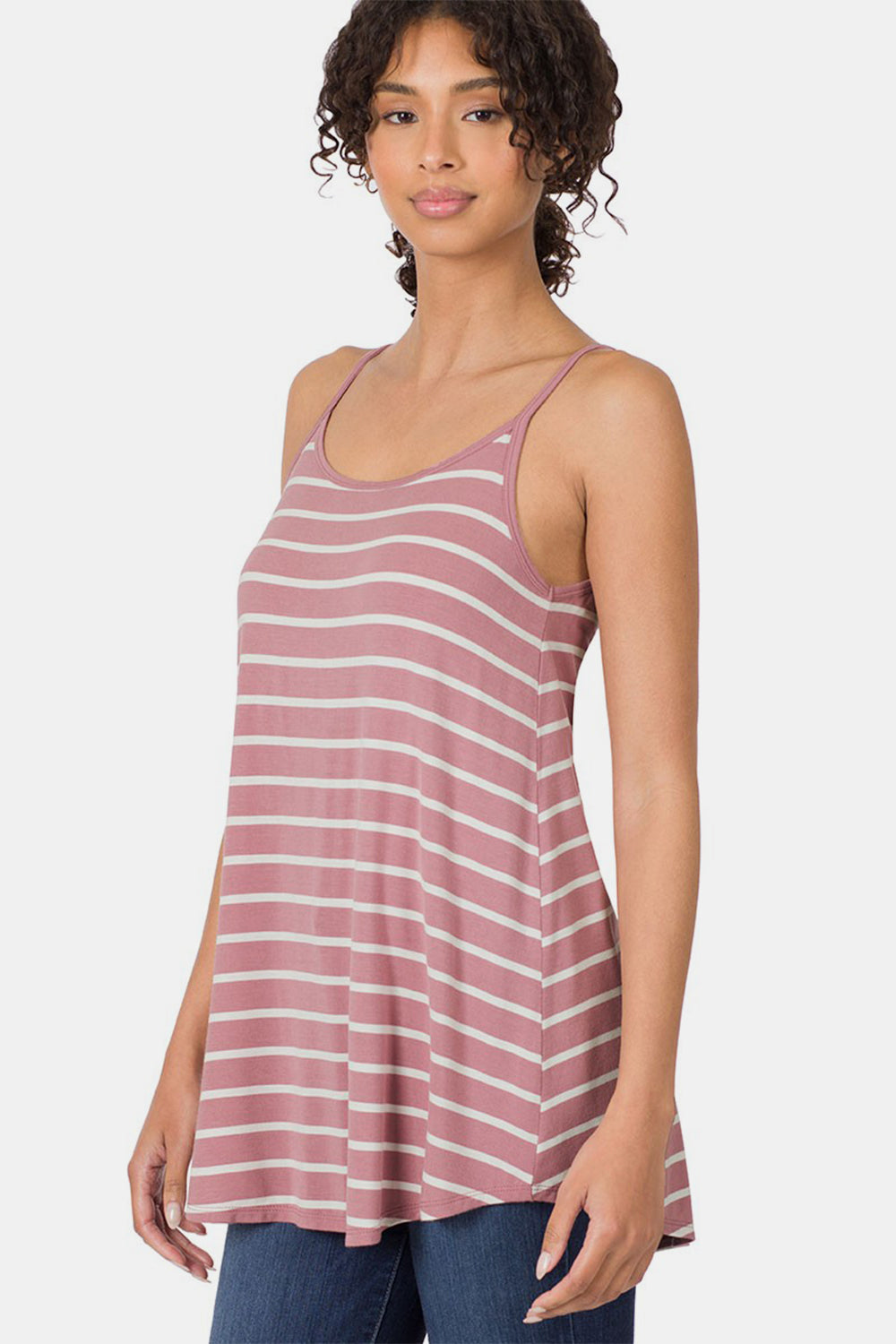 A person with curly hair wearing a chic Zenana Striped Curved Hem Cami in pink and white stands against a plain background, making it perfect for any summer wardrobe.