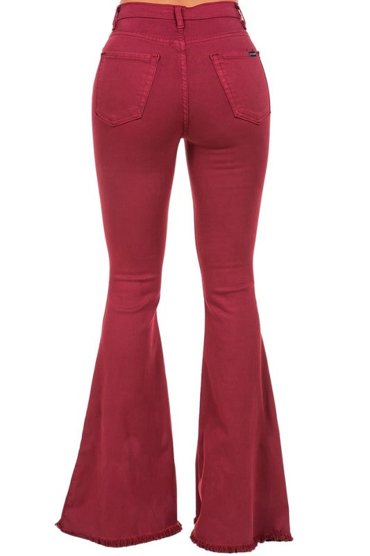 A person wearing high-rise, wine-colored Bell Bottom Jeans with frayed hems (Inseam 32), paired with open-toe shoes.